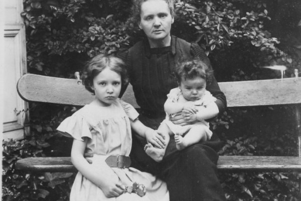 Marie Curie sitting with her two children on a bench.